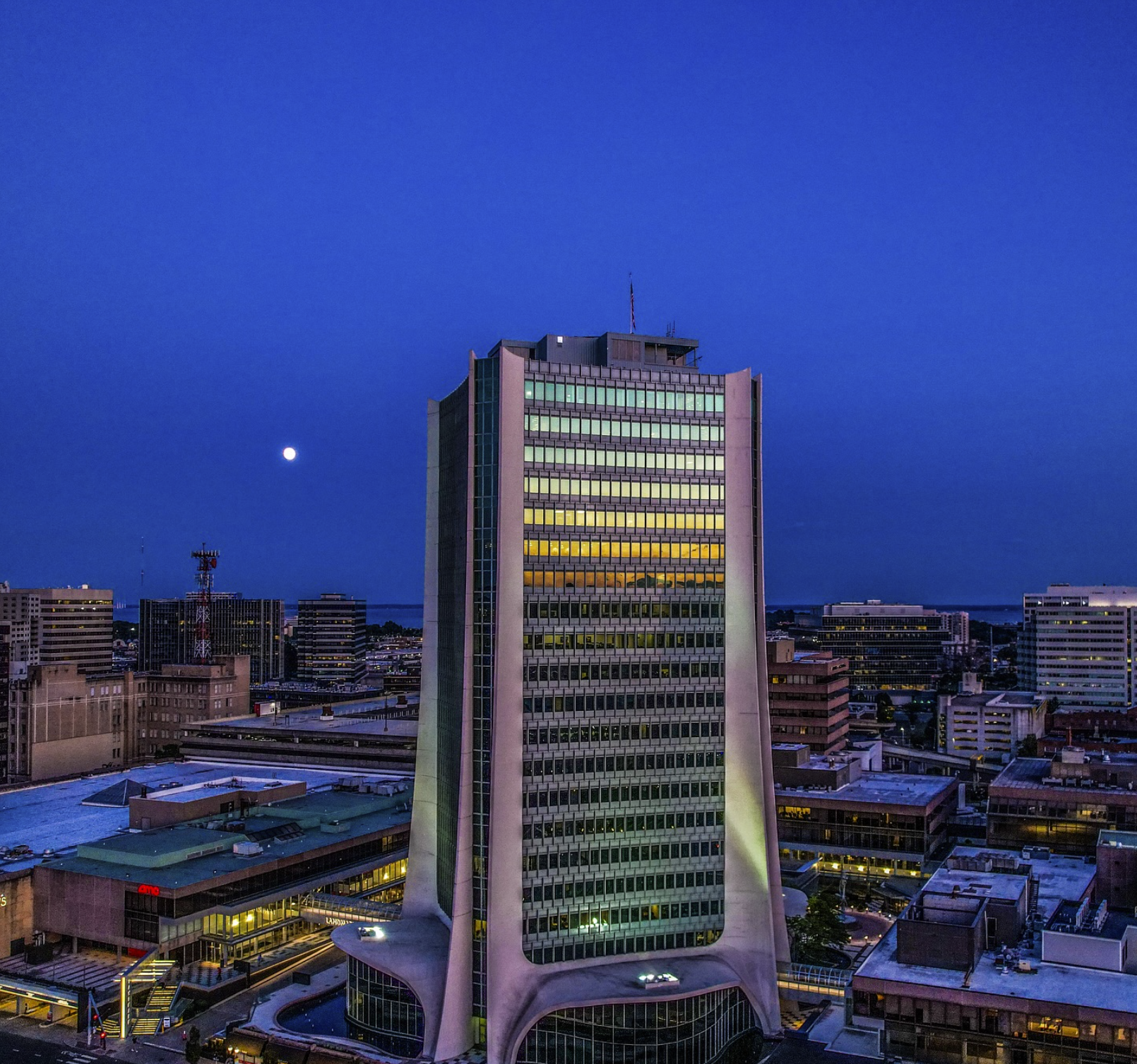 A twilight view of downtown Stamford features a prominent modern high-rise glowing against the evening sky, capturing the city’s sleek urban landscape and highlighting Stamford as a key hub for long-distance transportation to and from New York City.