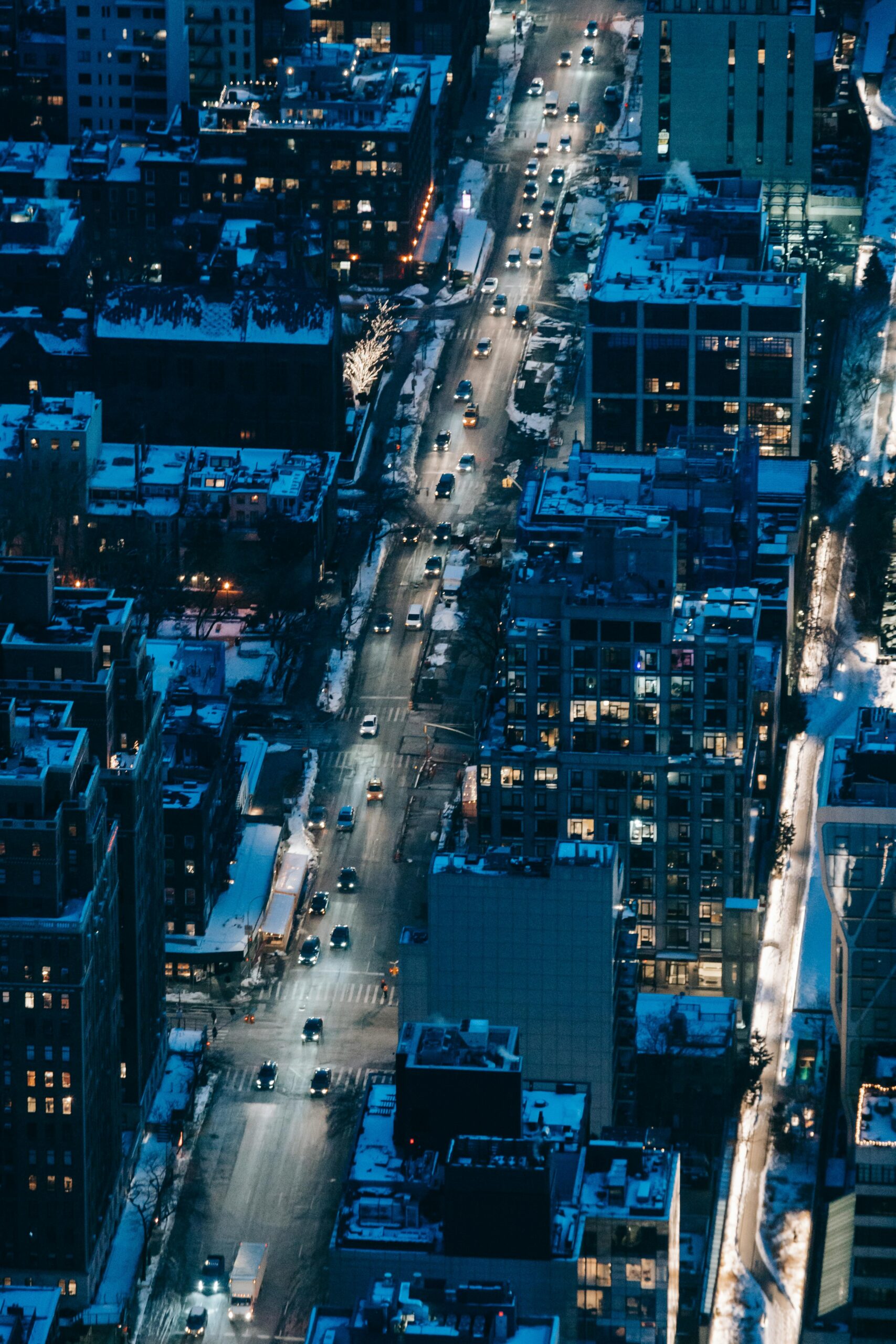 top down view of snow covered New York City during the night, drawing attention to the lack of traffic and pedestrians moving throughout its streets, highlighting the need for a private transportation service in Manhattan.